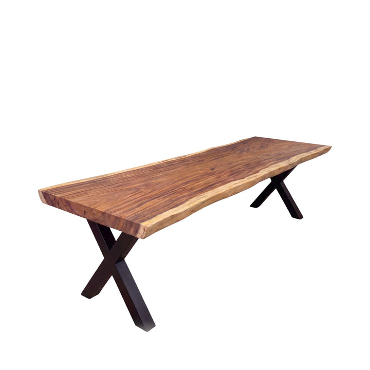 Front view of the Makai table showing its natural suar top and black metal X-shaped base in a darker finish variation.