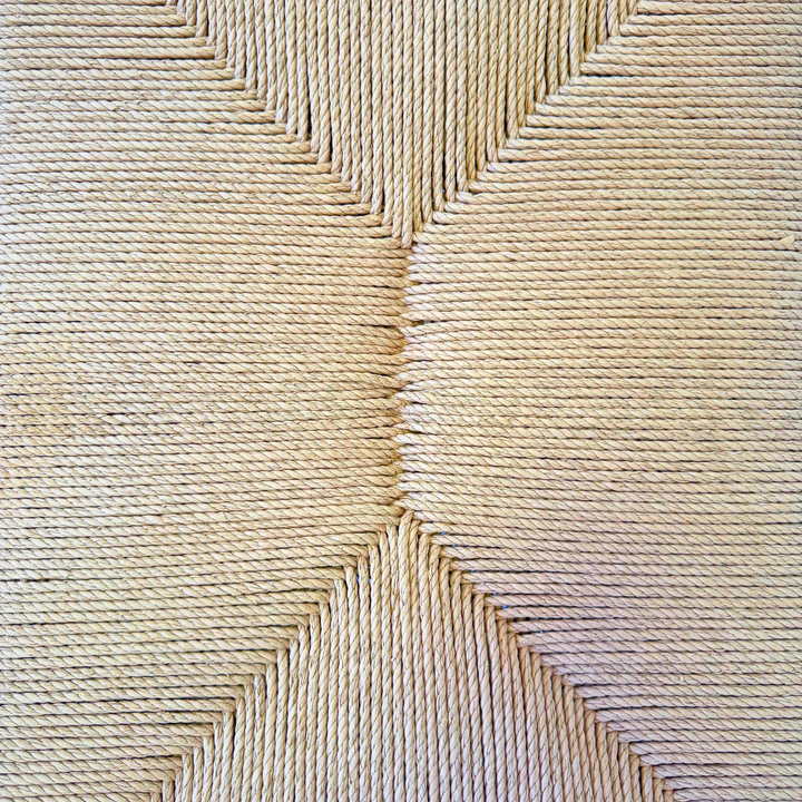 Seat close-up showing hand-woven paper-loom pattern and texture