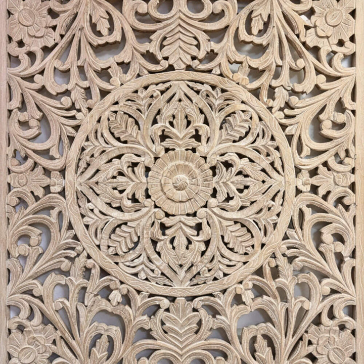 Close-up of the central mandala carving on the white-washed panel.