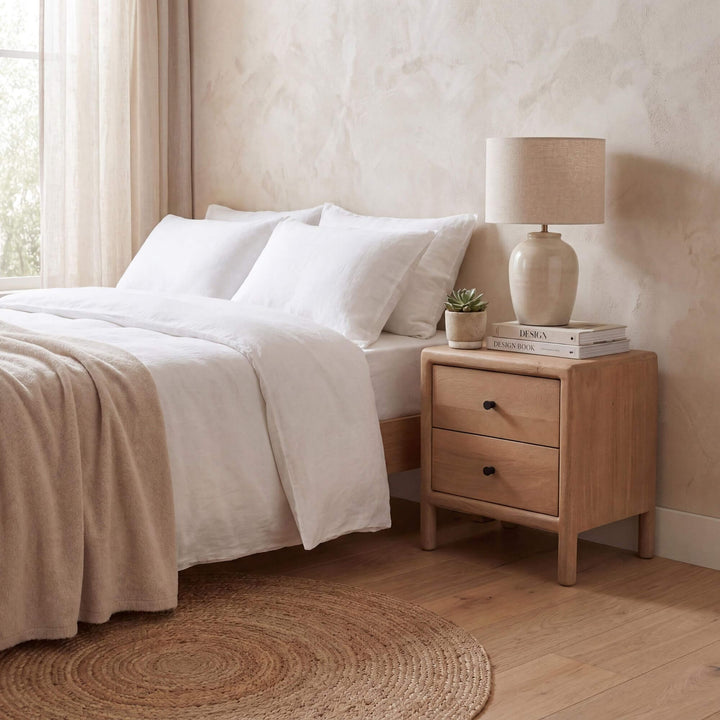 Styled bedroom setting featuring the mango bedside table beside a bed in a warm natural interior.