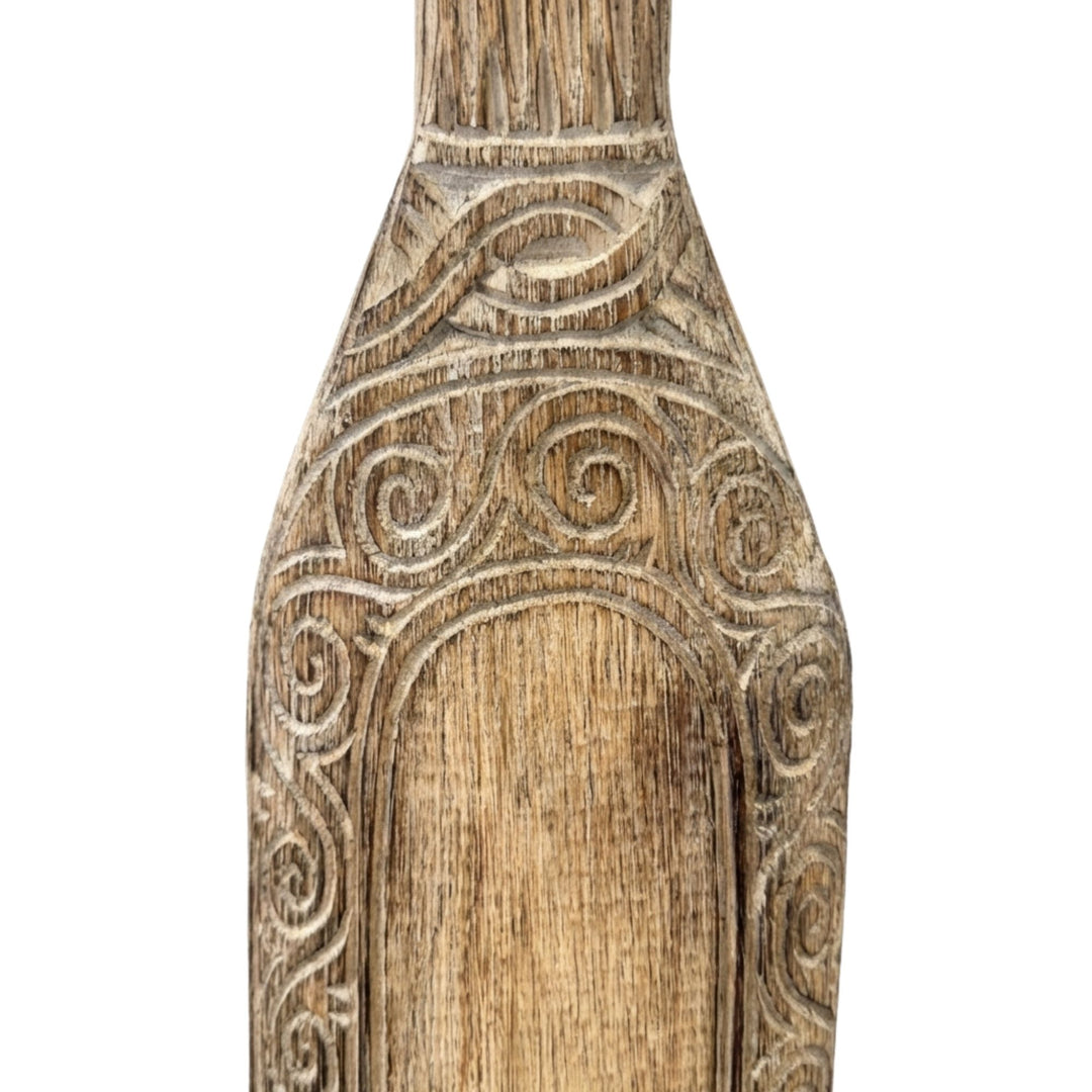 Close-up detail of the paddle blade highlighting the carved patterns and wood texture.