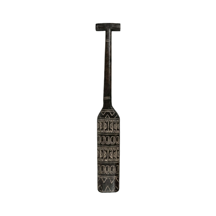 Front view of the Maui paddle showcasing its elongated carved design and dark wood finish.