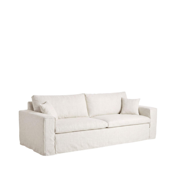 Front view of the Modena sofa in a light natural linen finish with loose back and decorative cushions