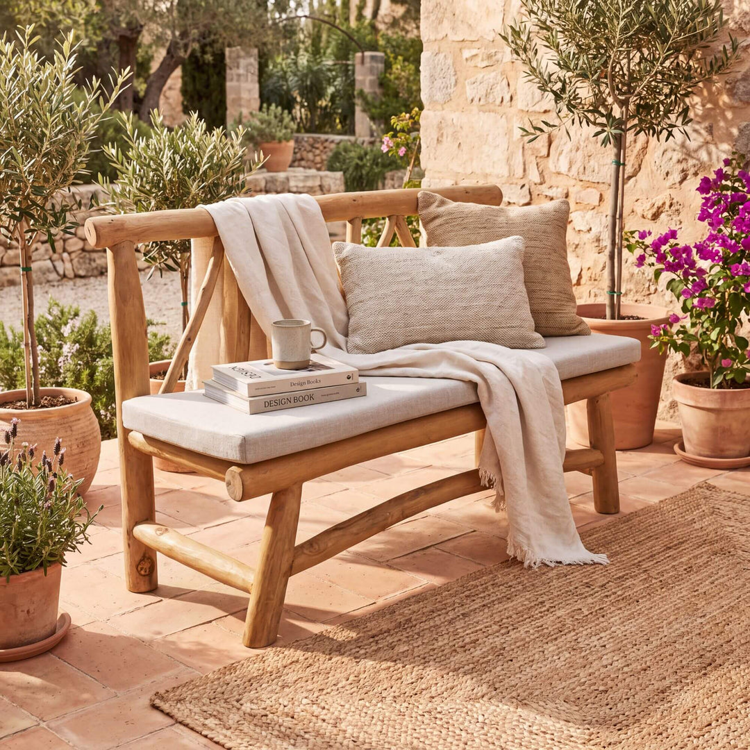 Molokai teak branch bench styled with cushions and a throw on a warm Mediterranean covered terrace