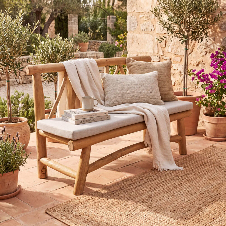 Molokai teak branch bench styled with cushions and a throw on a warm Mediterranean covered terrace