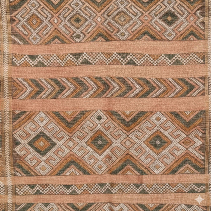 Close-up of the handwoven geometric motifs in terracotta and beige.