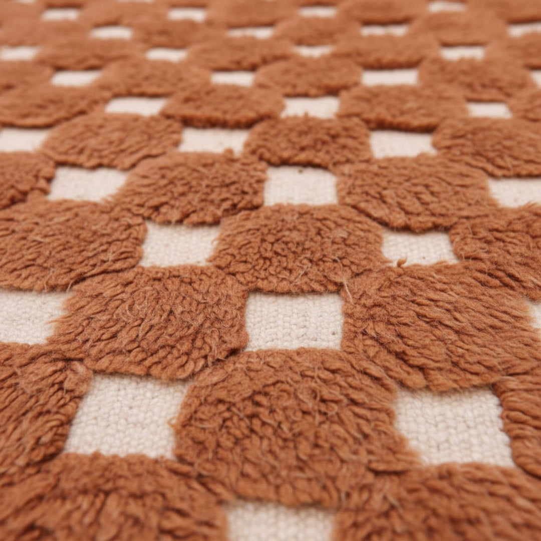 Close-up of the plush wool checker texture in terracotta and cream.