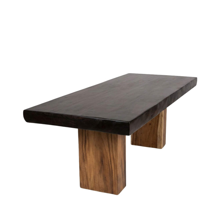 Front view of the Motu Iti black suar wood dining table showcasing its solid black tabletop and sculptural wooden legs.