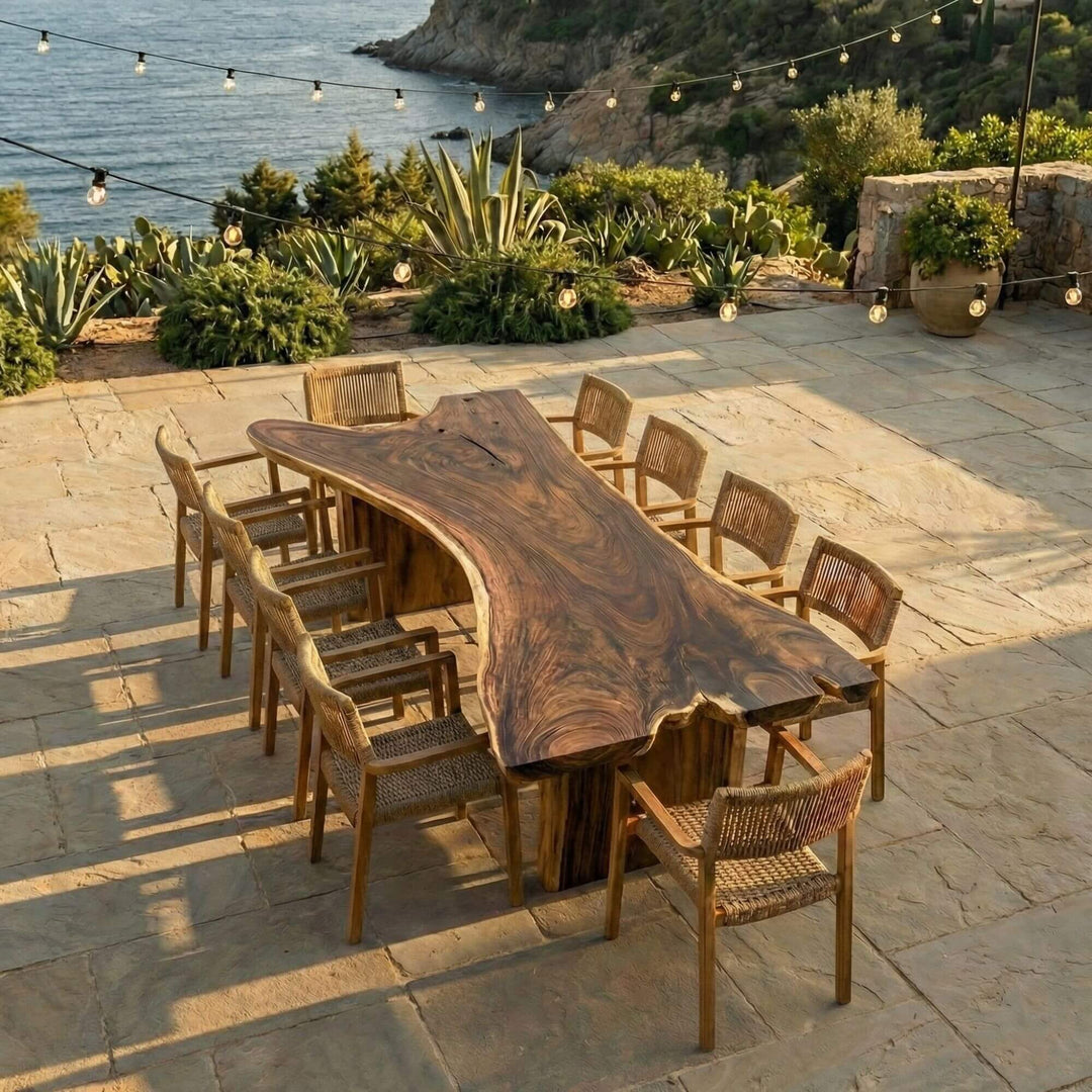 Outdoor dining setting featuring the Motu Nui table placed on a stone terrace overlooking the sea.
