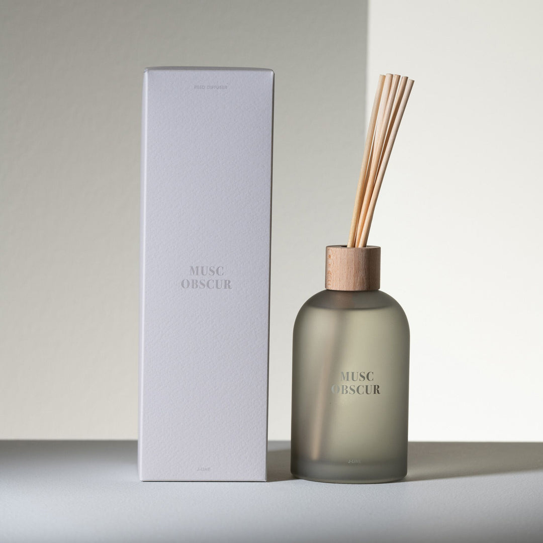 Musc diffuser placed beside its packaging in a minimalist interior setting.