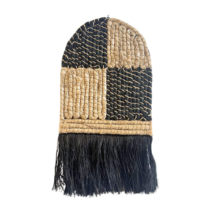 Merak Wall Deco handwoven from abaca, rattan, and cotton with natural and black patchwork design and fringe
