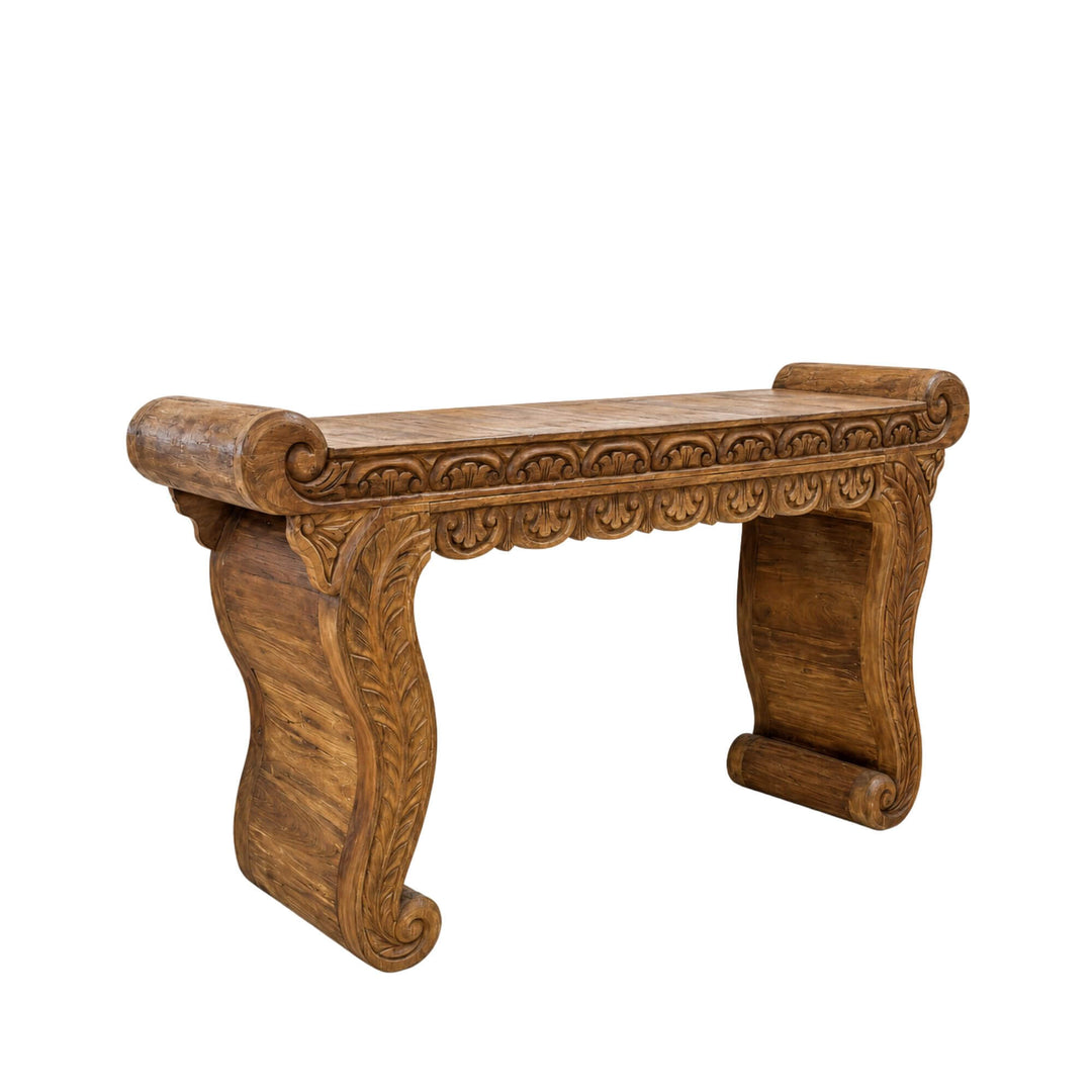 Front angled view of the Nirvana teak wood console with carved detailing, scroll-shaped edges, and sculptural curved legs