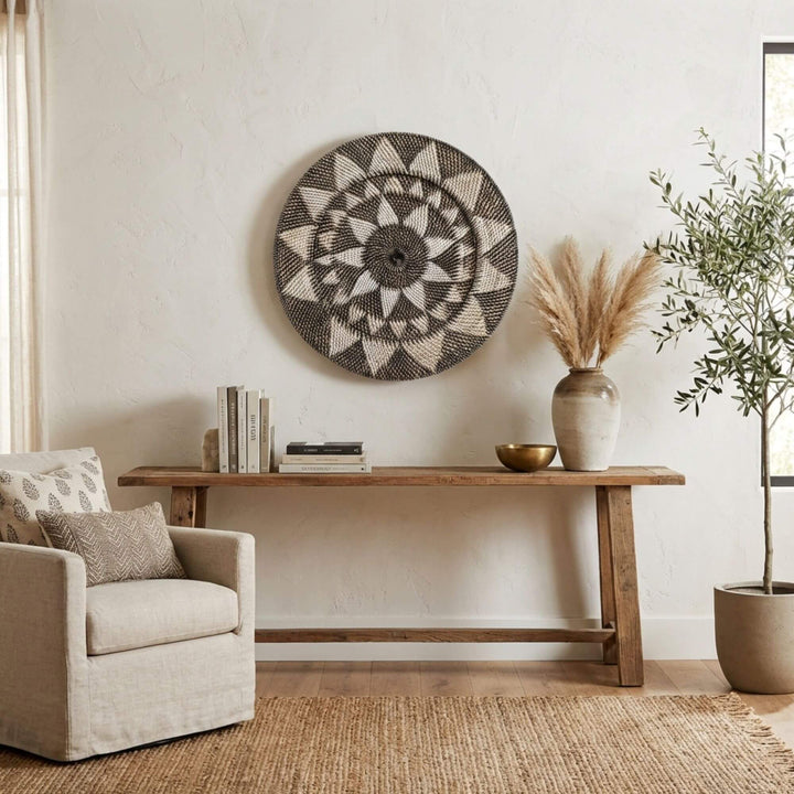 Living room with a beige armchair, wooden console table, and decorative Nyis collection plate wall art.