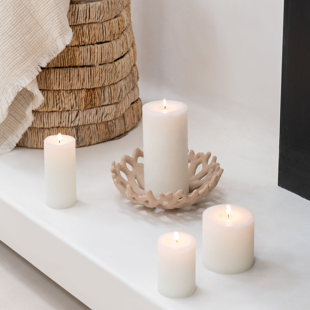 White candles on a white surface with a decorative candle holder.