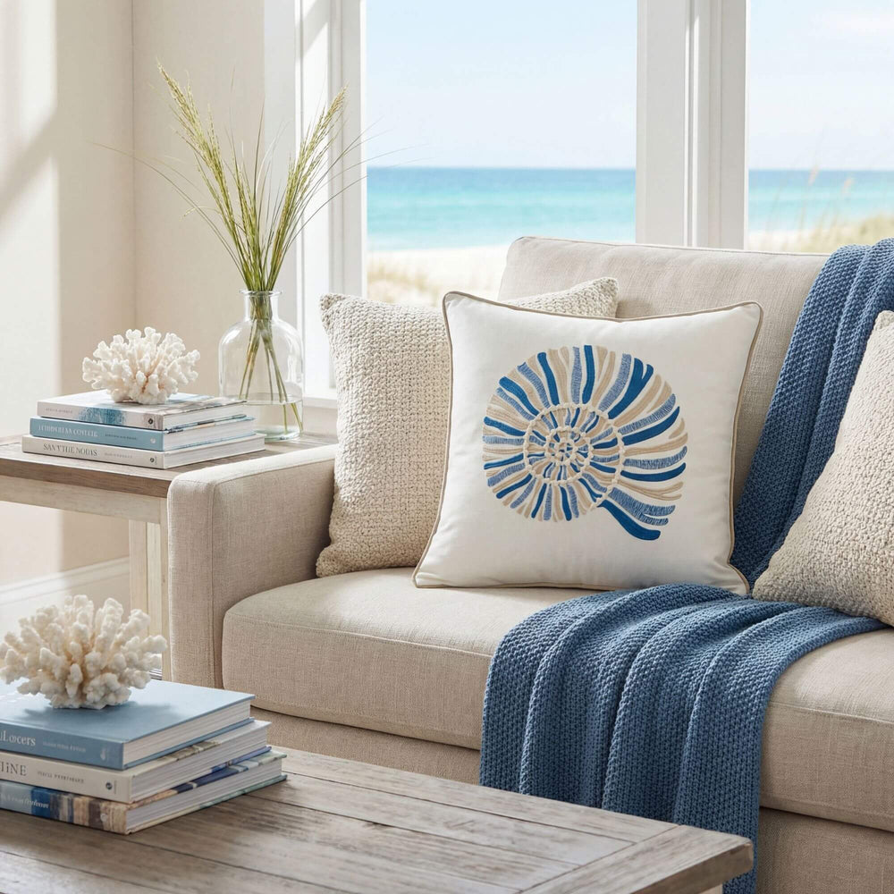 Front view of the Ocean Shell cushion showing its embroidered shell motif in blue and natural tones.