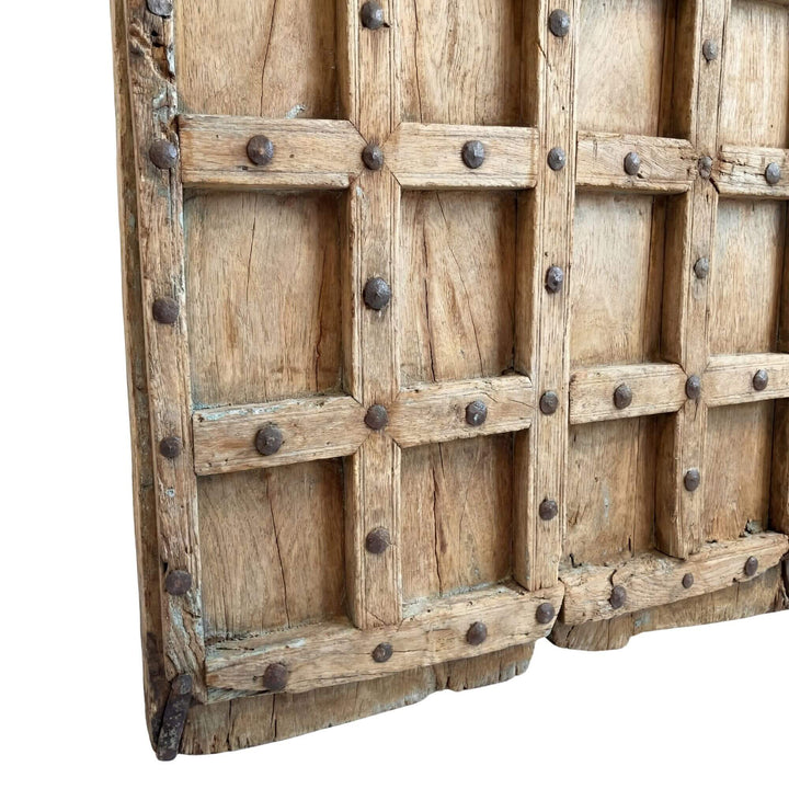 Close-up detail of the reclaimed sheesham wood surface and hand-forged metal stud pattern.