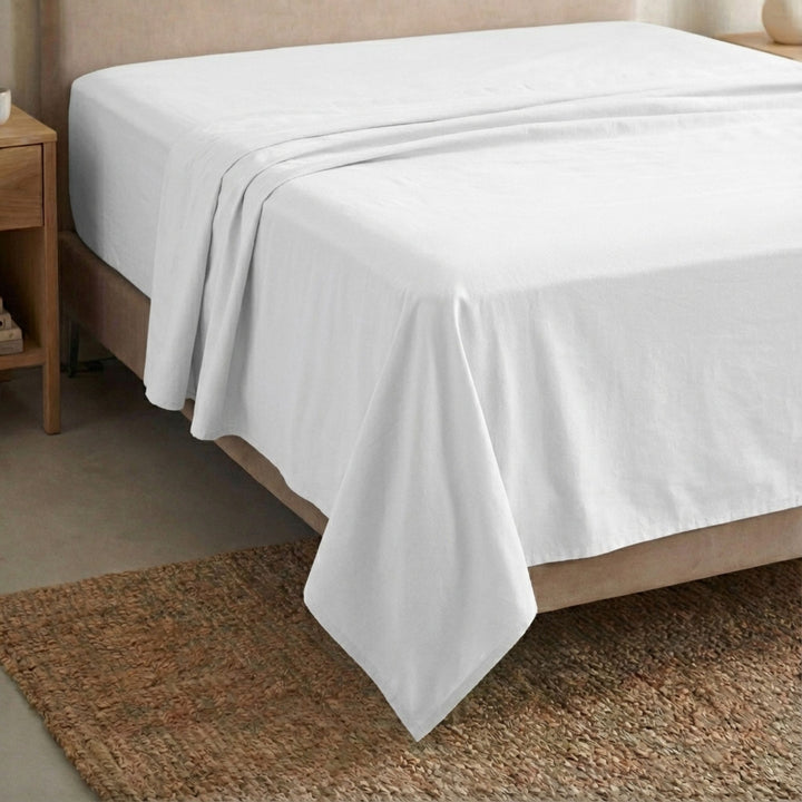 Full view of the Opera top sheet draped over a bed, showcasing its fluid cotton-linen texture.