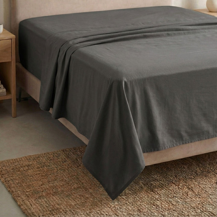 Full view of the Opera top sheet draped over a bed, showcasing its fluid cotton-linen texture.
