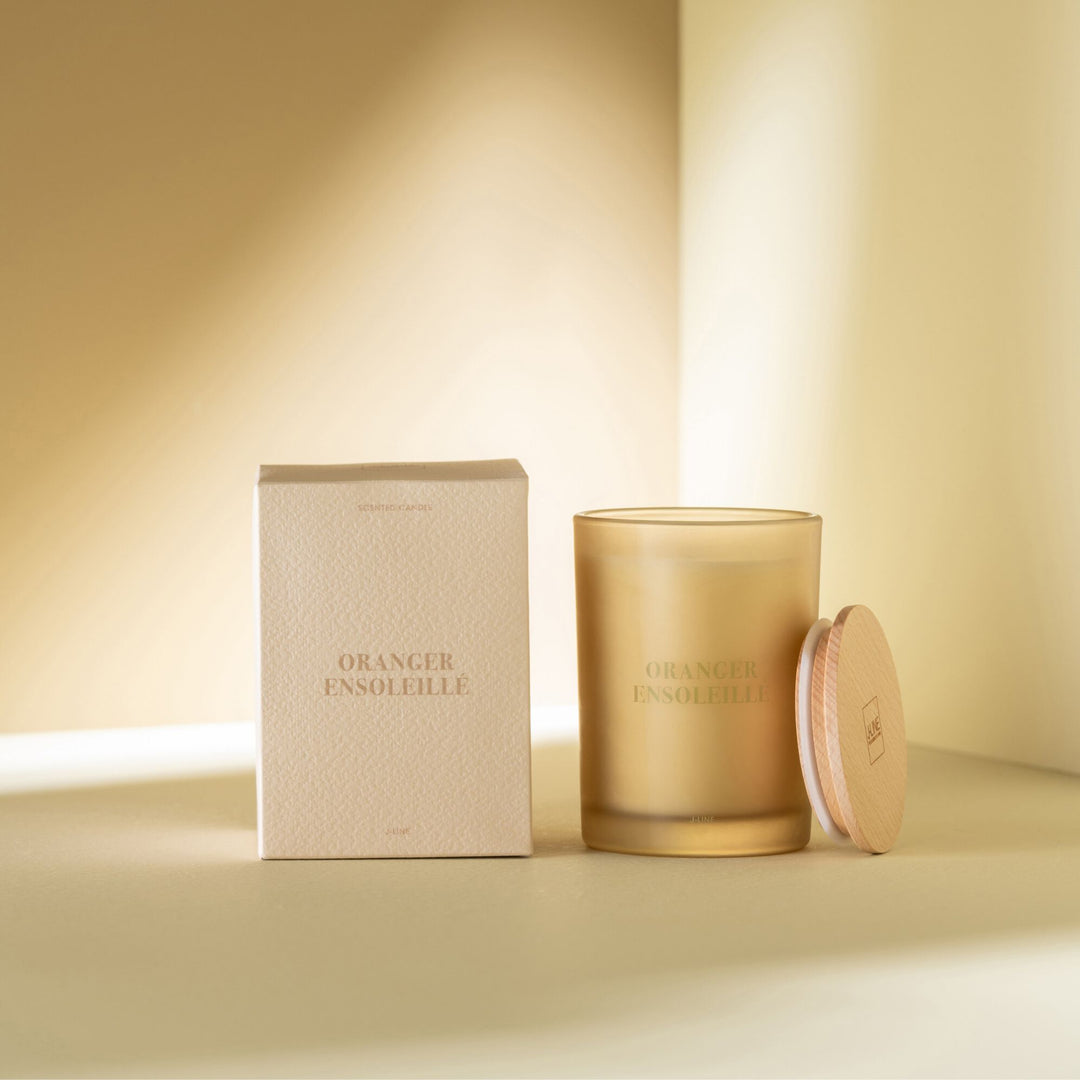 Candle and packaging displayed in a warm, sunlit interior.