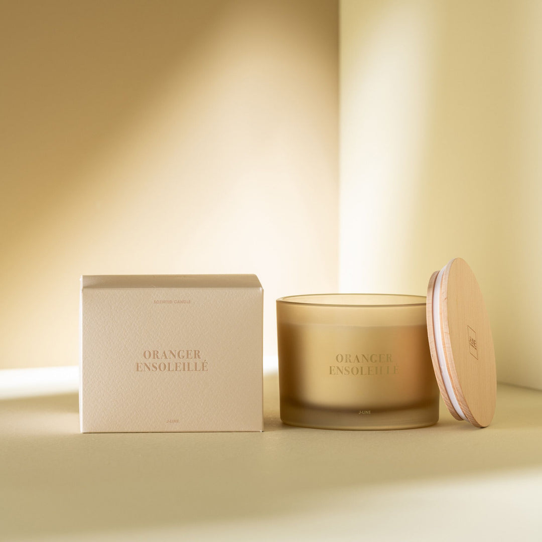 Candle and packaging displayed in a warm, sunlit interior.