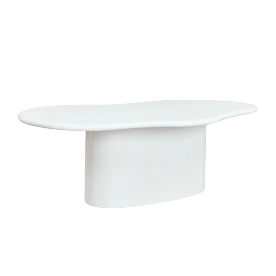 Front view of the organic cement dining table showing its sculptural curved shape and smooth mineral finish.