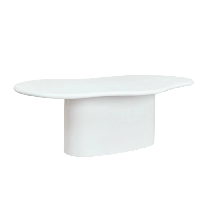 Front view of the organic cement dining table showing its sculptural curved shape and smooth mineral finish.