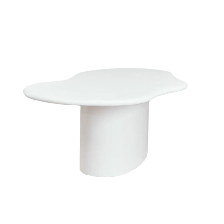 Angled view of the dining table highlighting its rounded silhouette and monolithic base.