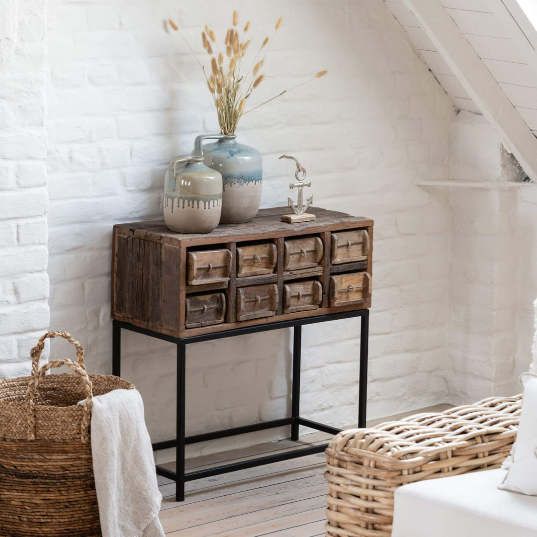 Otto Drawer cabinet with decorative items against a white brick 
