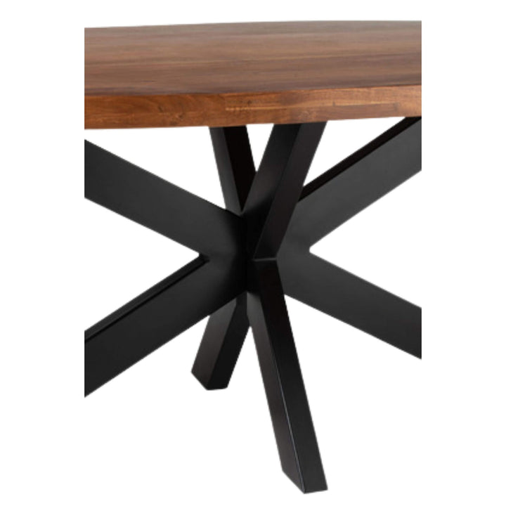 Close-up of black metal star base under acacia oval table