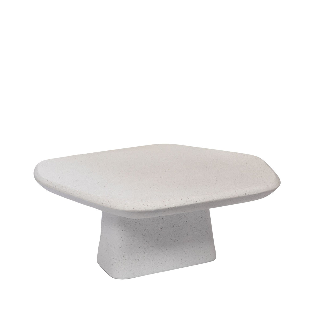 Front angled view of the Pietra coffee table showing its low sculptural base and softly rounded rectangular top.