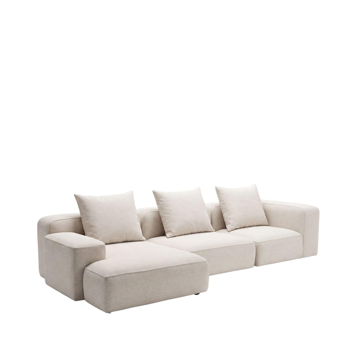 Front angled view of the Positano chaise longue sofa with deep seating, neutral upholstery, and loose back cushions