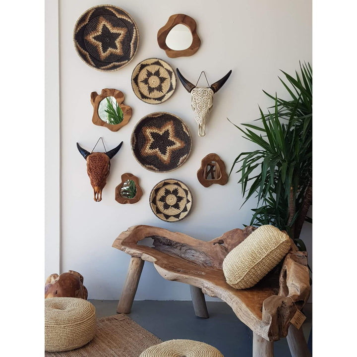 Interior wall with hand-carved bone skull, teak mirrors, and woven baskets as tribal decor.