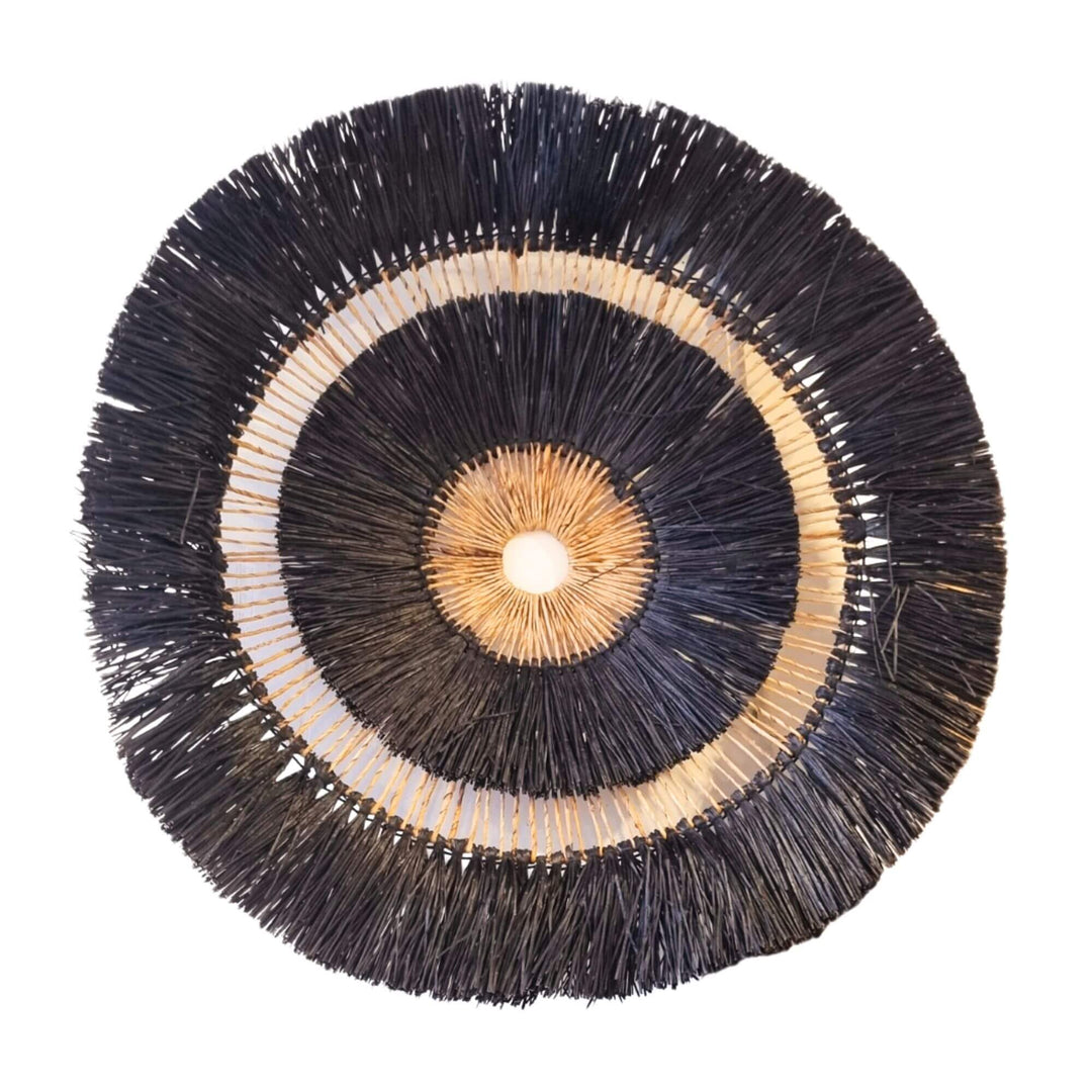 Large round wall decor made of black and natural mendong fibers.