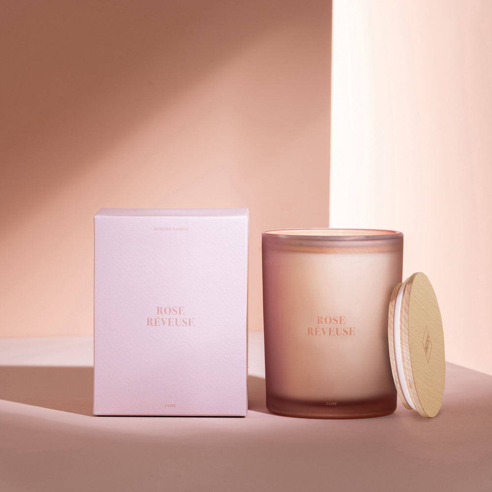 Styled image of the Rose Rêveuse candle beside its box in a warm, elegant setting.