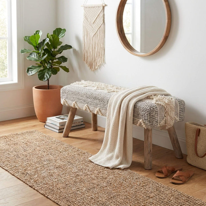 Front view of the Saga bench showcasing its woven jute and cotton seat and teak branch wood legs.