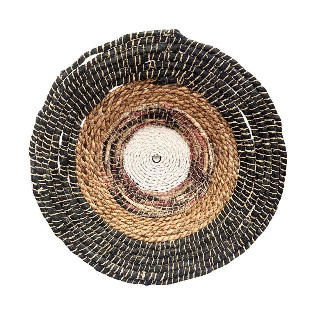 Handwoven Sanggar Wall Deco made from abaca, rattan, and cotton in circular natural and black pattern.