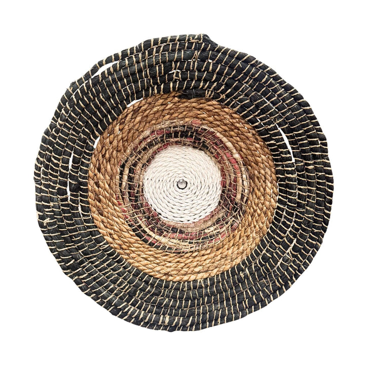 Handwoven Sanggar Wall Deco made from abaca, rattan, and cotton in circular natural and black pattern.