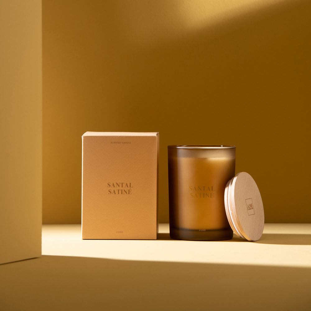 Candle and packaging displayed in a warm-toned interior setting.