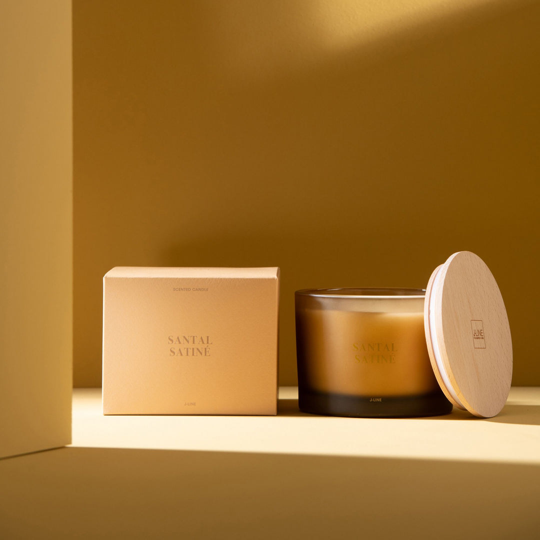 Candle and packaging displayed in a warm-toned interior setting.