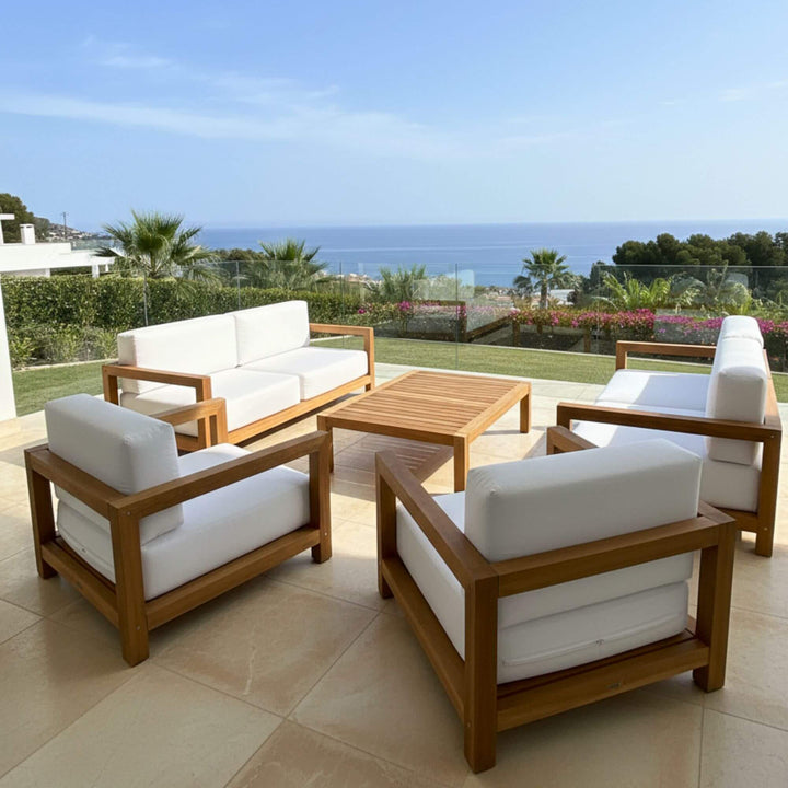 Outdoor setting showcasing the Santorini teak sofa on a terrace with sea views.