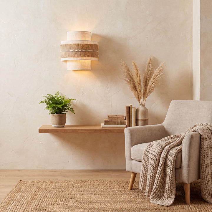 Styled interior setting featuring the Sapi wall lamp above a wooden shelf in a warm natural living space.