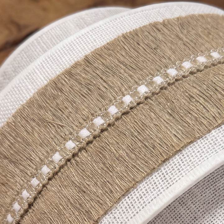 Close-up detail of the wall lamp showing the woven fabric, jute fringe, and decorative openwork band.