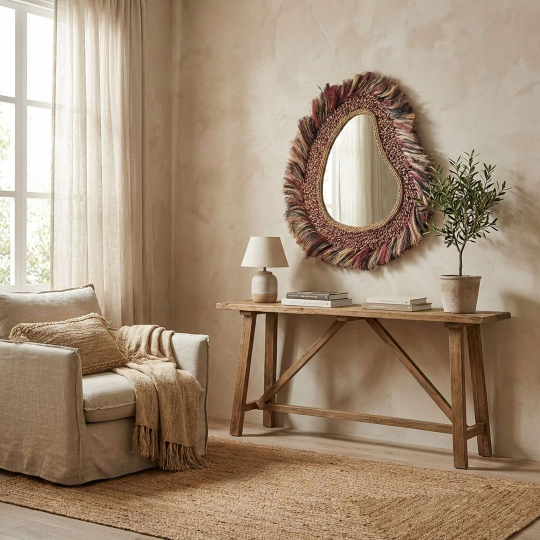 Living room with a textured wall, round decorative Sawana mirror, wooden console table, and armchair.