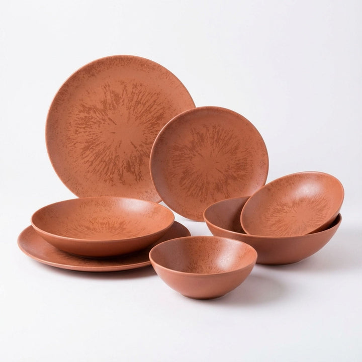 Sebuku Terra ceramic tableware set with plates and bowls in warm terracotta tones.