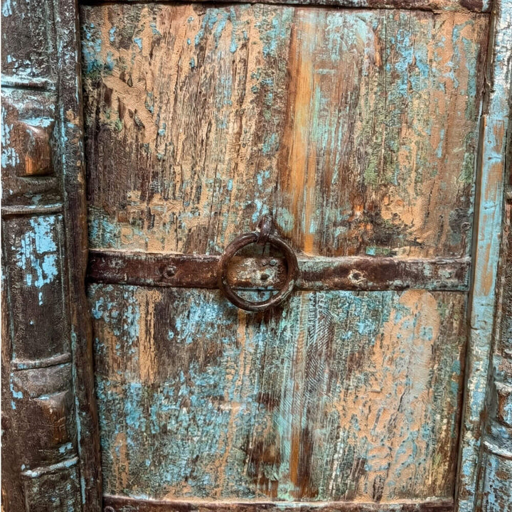 Close-up detail of the Seidon wardrobe doors highlighting the aged paint texture and carved wood patterns.