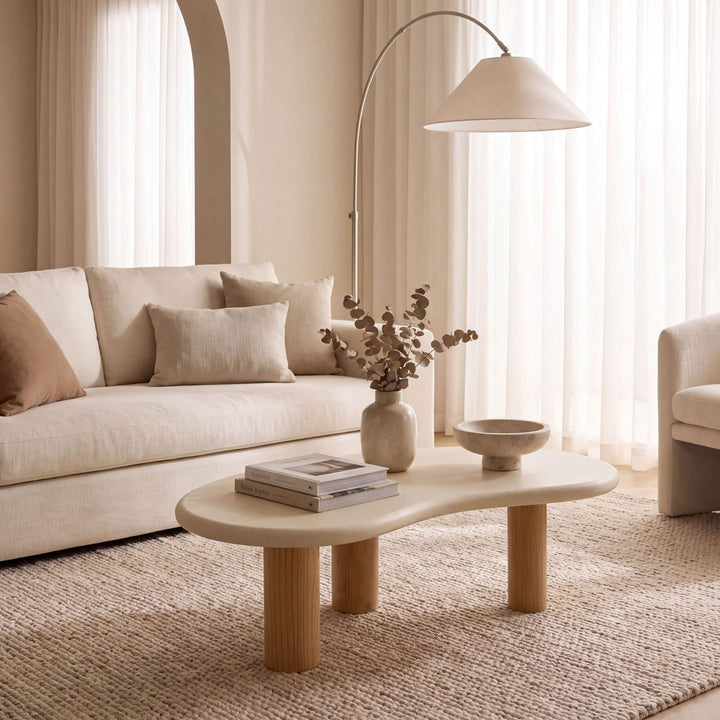 Senja microcement coffee table styled with books and decorative objects in a warm neutral living room