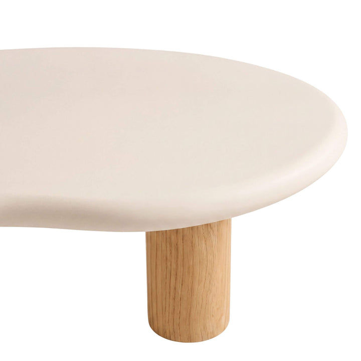 Close-up of the Senja coffee table showing its rounded microcement edge and natural sungkai wood leg