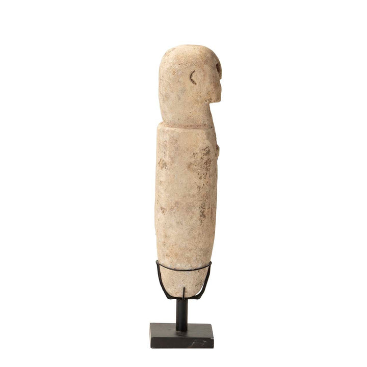 Side view of the stone stand figure showing raw texture and elongated form.