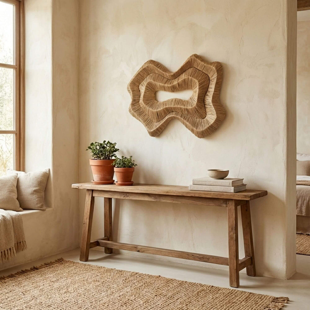 Nestled corner of a room with a wooden bench, potted plants, and Shoal natural wall art.