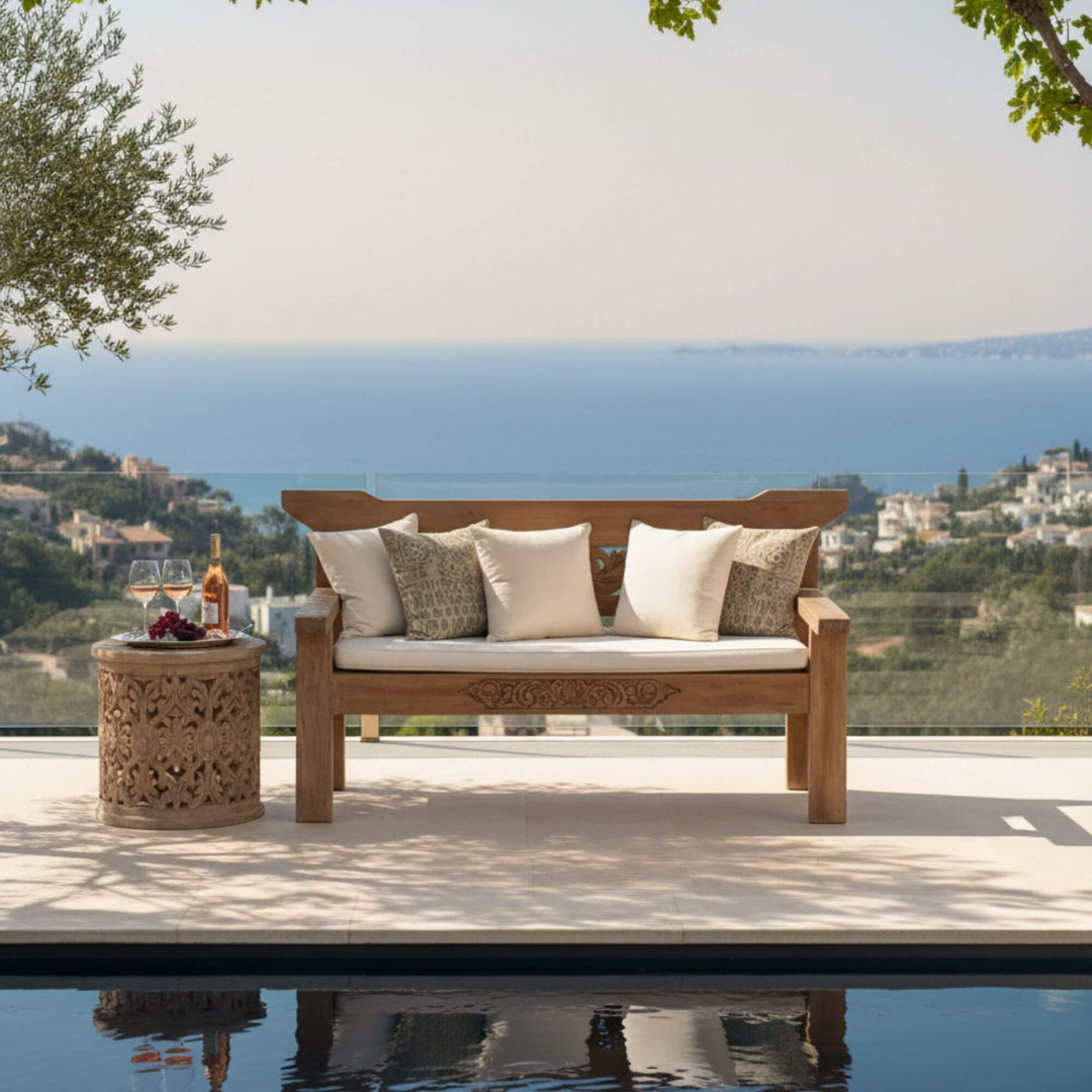 Styled outdoor view of Skopelos Indonesian Carved Teak Wood Bench placed on a terrace overlooking the sea.